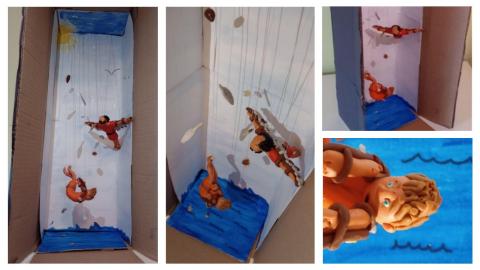 A vertical cardboard box model, showing a plasticine-style Daedalus model watch on as Icarus falls. Icarus' facial expression and body posture are  particularly dynamic and moving. Both models are suspended from strings, as are a number of white feathers.